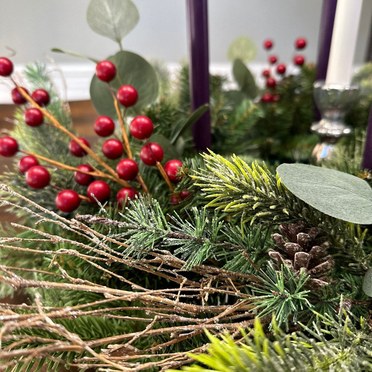 Advent wreath - detailed photo of the red berries, twigs and pinecones amongst the evergreens