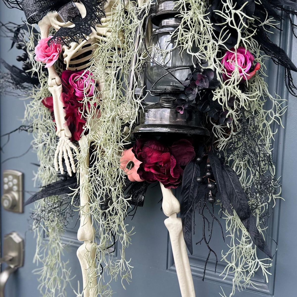 Halloween skeleton door wreath with a lantern that lights up, Moveable 36" skeleton holds light and is nestled in creepy moss and pink roses