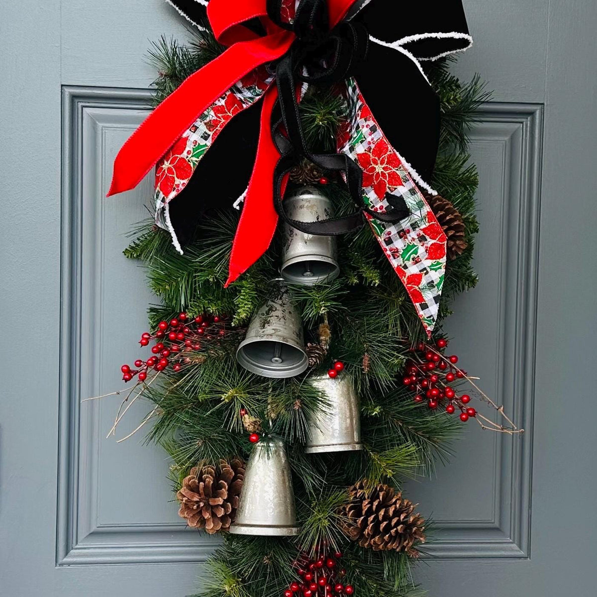 Christmas front door swag with Silver metal bells. Mixed pine with natural pinecones and red berries with twigs topped with a stunning bow!