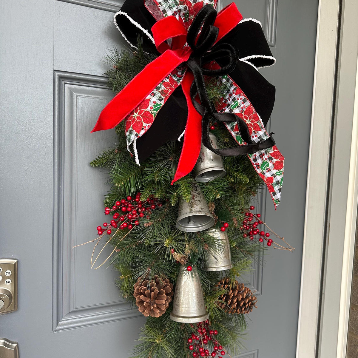 Christmas front door swag with Silver metal bells. Mixed pine with natural pinecones and red berries with twigs topped with a stunning bow!