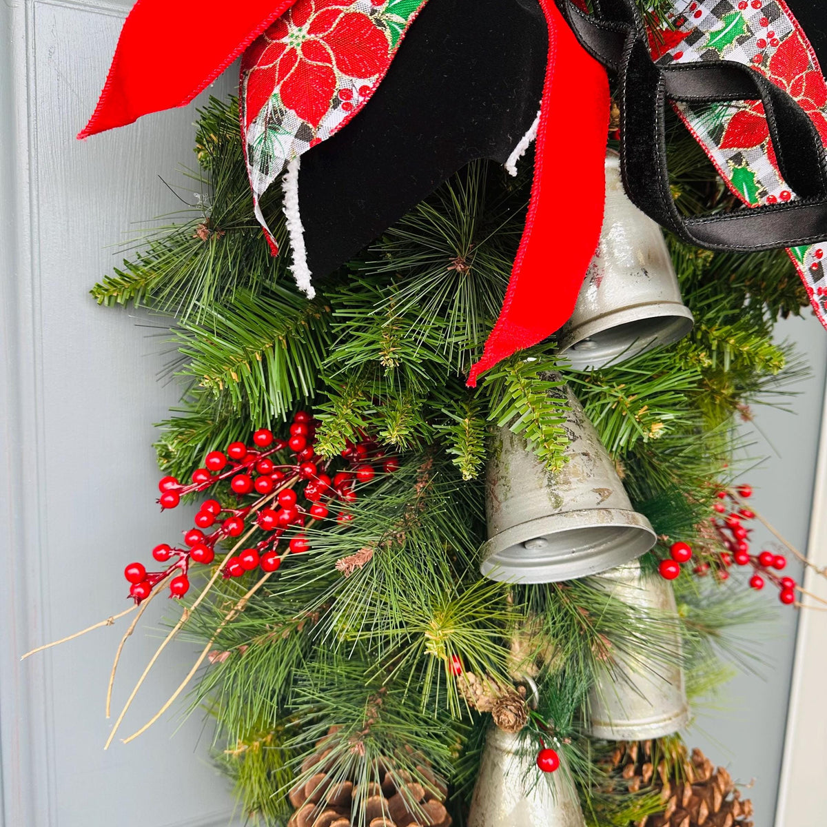 Christmas front door swag with Silver metal bells. Mixed pine with natural pinecones and red berries with twigs topped with a stunning bow!